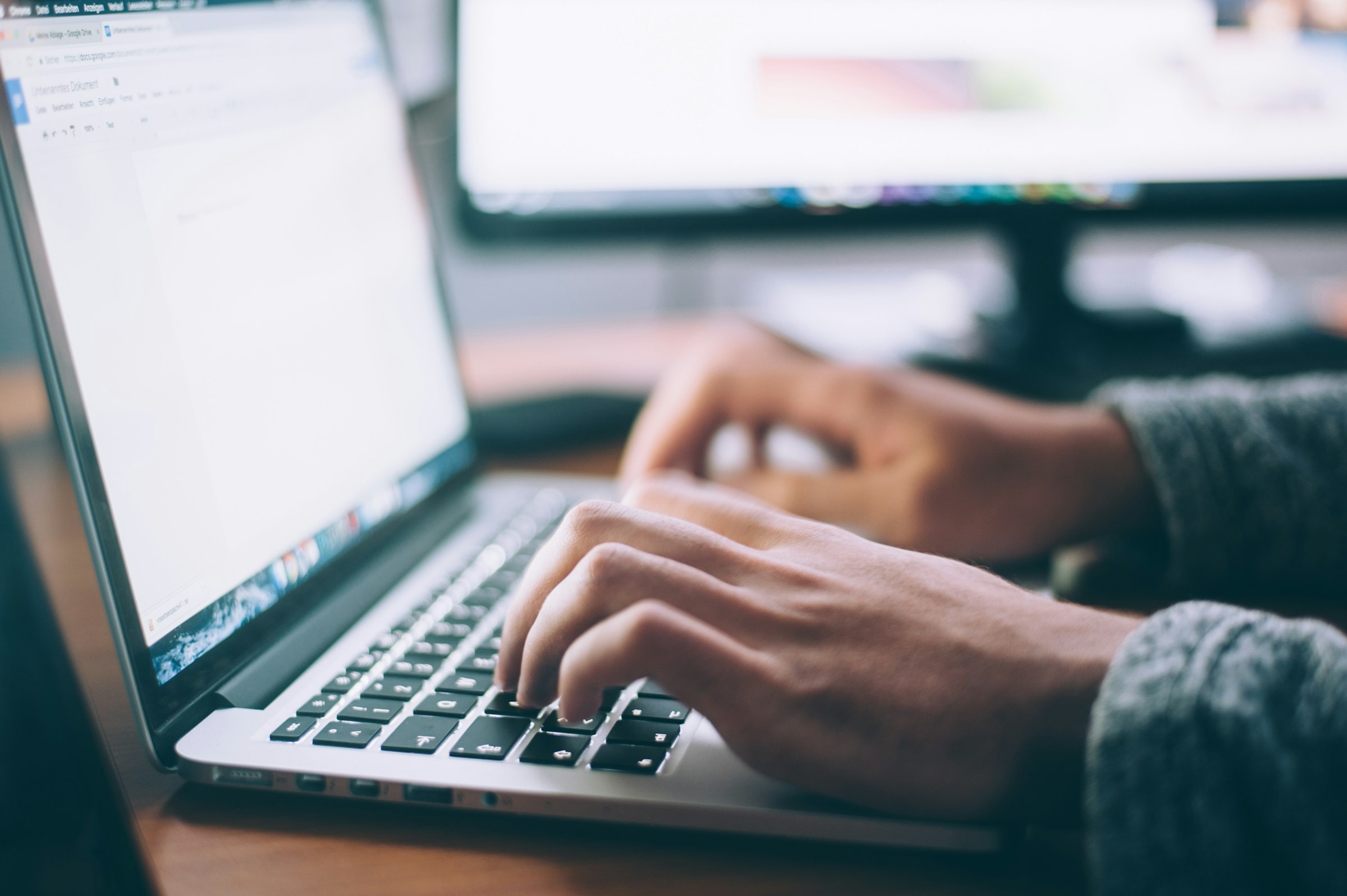 Author writing on a laptop at a wooden desk